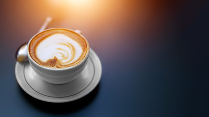 Aromatic cappuccino with latte foam in white cup on low key dark background. Copy space. Sun light effect. Coffee break concept, early wake up, arabica coffee bar