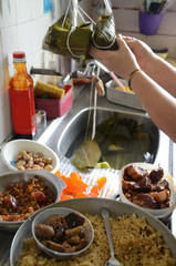 Zongzi or rice dumpling is glutinous rice with sweet or savoury fillings wrapped in bamboo or reed leaves. A housewife making a traditional dumpling with fresh ingredients.