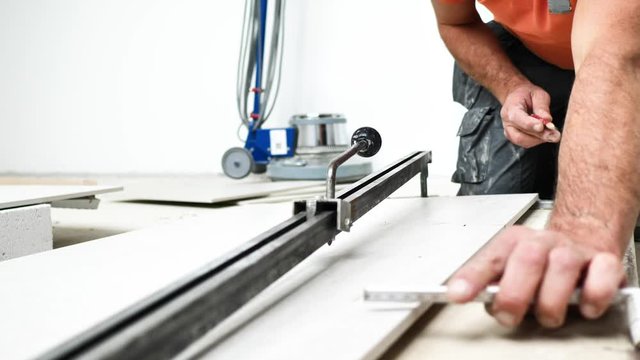 Handwerker schneidet grosse fliesen mit Fliesenschneider in einem neubau haus 4k Video in zeitlupe