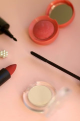 Obraz na płótnie Canvas Make-up products on pale pink background: pink blush, mascara, highlighter, lipstick, eyeliner and fashionable beret. Selective focus.