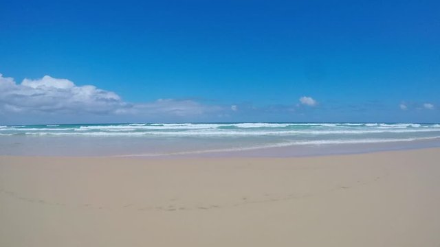 Stunning 4k footage driving along Seventy Five Mile Beach (75 Mile Beach) on Fraser Island off the coast of Queensland, Australia, looking out to the sea. Beautiful clear day and waves on the beach.