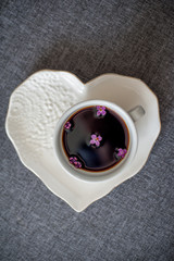  A white, beautiful ceramic cup with coffee and lilac flowers