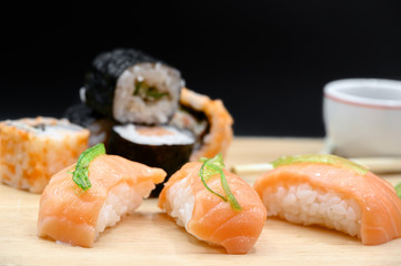 Close Up Of Various Types Of Japanese Fresh Prepared Sushi on wooden table on black isolated background .