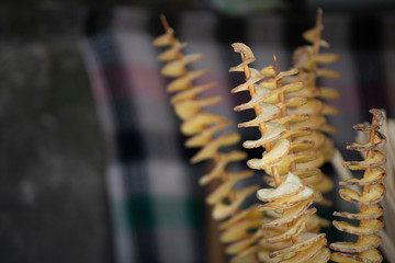 Fried potatoes are sold outside in a cart.