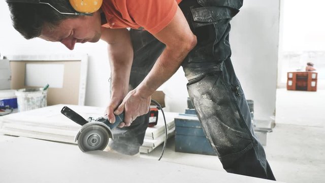Fliesenleger schneidet fliesen mit einem winkelschleifer (flex) 4k video in zeilupe