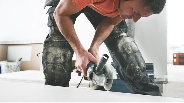 Fliesenleger schneidet fliesen mit einem winkelschleifer (flex) 4k video in zeilupe