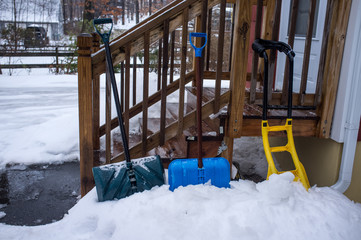 3 snow shovels in snow and ice by the backdoor steps in winter
