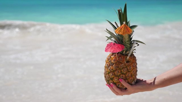Sweet pineapple cocktail in hand with caribbean beach background. Travel destinations. summer vacation