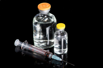 Large Medication Vials With Syringe On Dark Refelctive Surface