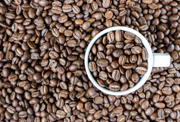 background. defocusing. Coffee beans in a white cup and on the table.