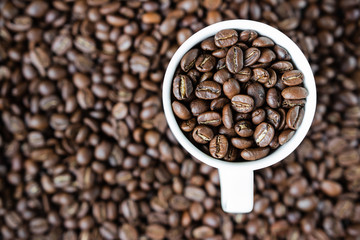 background. defocusing. Coffee beans in a white cup and on the table.