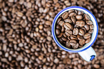 background. defocusing. Coffee beans in a white cup with a blue stripe. coffee beans on the table.