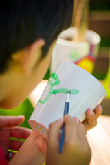 Child painting a cup arts and crafts colorful paint
