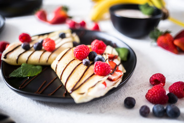 Crepes on a plate garnished with berries and mint