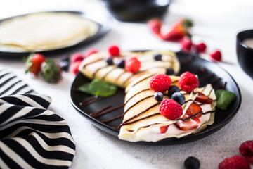 Crepes on a plate garnished with berries and mint