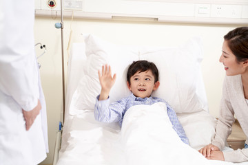 five year old asian kid waving good-bye to doctor