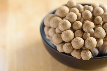 Raw brown shimeji mushroom in a bowl on wooden background