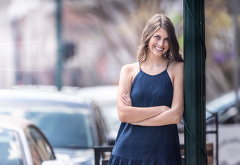 Beautiful girl in a city leaning against a light pole, copy space