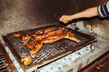 Traditional suckling pig cooked on the charcoal grill. The little pig is roasted whole on an open fire. Organic pig on the spit.
