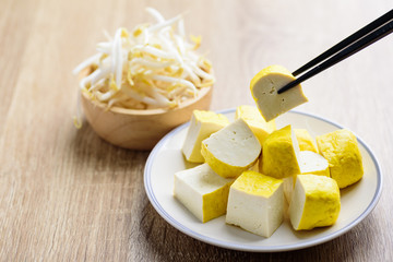 Sliced tofu picking with chopsticks and fresh mung bean sprout in a bowl,  food ingredient for Asian vegan food