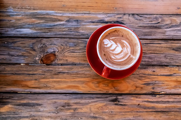 Red cup of coffee art on wooden table. Image on top view.