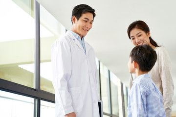 young asian doctor talking to mother and son in hospital