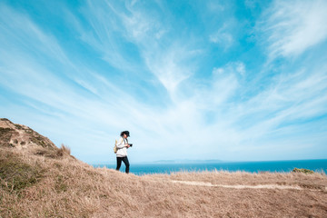 Woman photographer hiking on Makara beach, Wellington, NZ