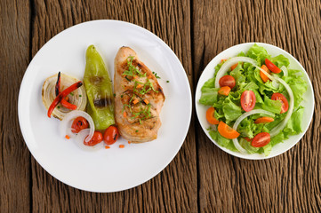 Grilled chicken on a white plate with tomatoes, salad, onion, chili and sauce.