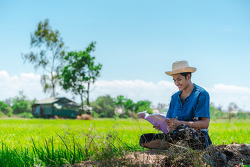 Naklejka na ściany i meble Asia farmers in field using digital tablet,Read a book