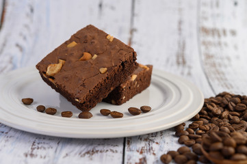 Chocolate brownies on a white plate and coffee beans.