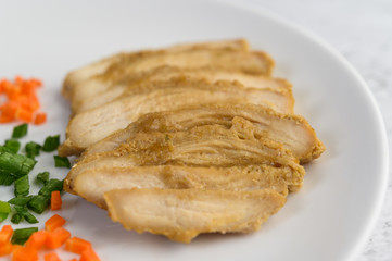 Steamed chicken breast on a white plate with spring onions and chopped carrots