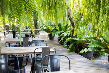Wooden tables and chairs in garden at coffee shop.