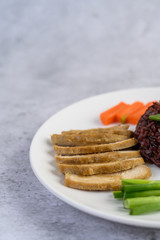 Black rice on a plate with pumpkin, peas, carrots, baby corn and steamed chicken breast.