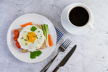 A fried egg laying on a toast, topped with pepper seeds with carrots and spring onions.