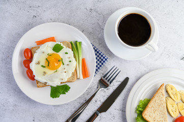 A fried egg laying on a toast, topped with pepper seeds with carrots and spring onions.