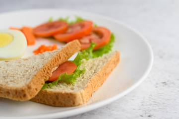Boiled eggs, bread, carrots, and tomatoes on a white plate with a knife and fork.
