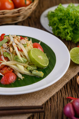 Papaya Salad (Som tum Thai) on a white plate on a wooden table.