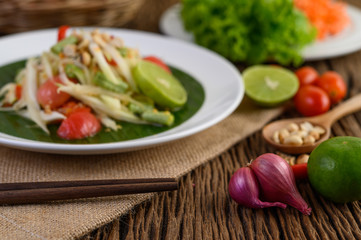 Thai style spicy food, Som Tum food concept, props decoration Garlic, lemon, peanuts, tomatoes, and shallots on wood table