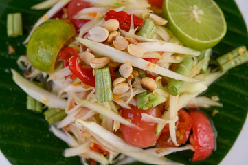Papaya Salad (Som tum Thai) on a white plate on a wooden table.