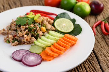 Spicy Minced Pork Salad on a white plate on wooden table.