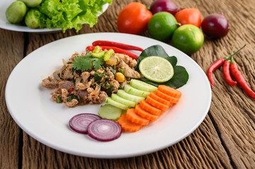 Spicy Minced Pork Salad on a white plate on wooden table.
