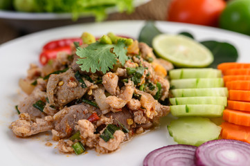 Spicy Minced Pork Salad on a white plate on wooden table.