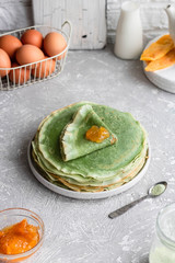 Fototapeta na wymiar Green pancakes with matcha tea and mango jam