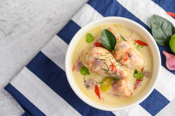 Tom Kha Kai in a bowl with kaffir lime leaves, lemongrass, red onion, galangal and chilli.