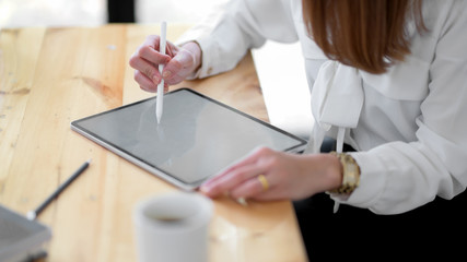 Fototapeta na wymiar Close up view of freelancer drawing on mock up digital tablet on wooden desk