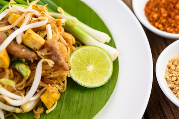 Pad Thai in a white plate with lemon on a wooden table