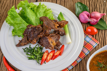 Beef fried Thai food on a white plate with spring onion, kaffir lime leaves, chilies, salad, red onions and tomatoes. Selective focus.