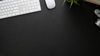 Top view of workplace with computer keyboard, copy space and camera on black table
