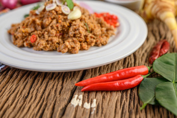Spicy Minced Pork Salad on a white plate with red onion, lemon grass, garlic, yardlong beans, kaffir lime leaves, and spring onion
