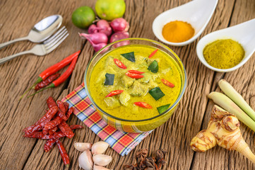 Green curry in a bowl and spices on wooden table.